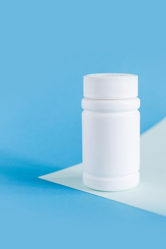 white medicine bottle mockup on blue background, pill bottles without label design, copy space